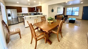 A modern kitchen with a central island, wooden dining table, and chairs. - Garage Studio near OUSHC Hospital (Oklahoma City)