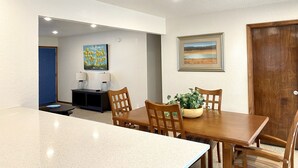 A dining area with a table and chairs, a blue door, and two paintings on the wall. - Garage Studio near OUSHC Hospital (Oklahoma City)