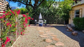 A garden with a gravel path, a table with chairs, and a fence. - Ar`s Artsy Downtown Bungalow 5 (Phoenix)
