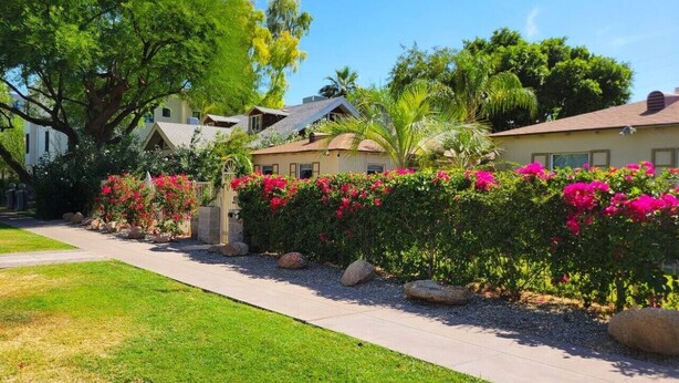 A residential area with a paved walkway, lush greenery, and houses with visible windows and roofs. - Ar`s Artsy Downtown Bungalow 5 (Phoenix)