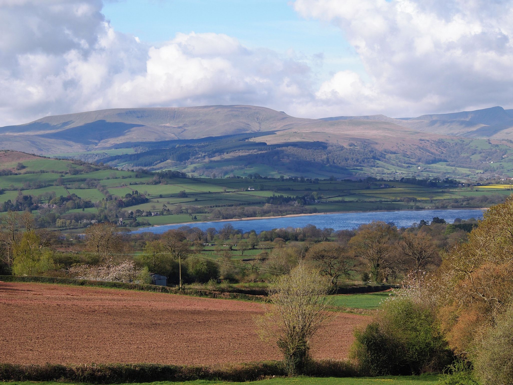 A rural landscape with rolling hills, a river, and scattered buildings.