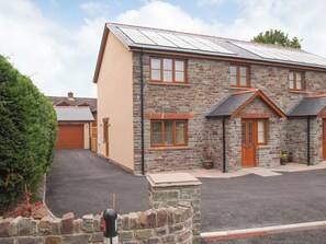 A two-story stone house with a garage, a driveway, and a well-maintained garden. - 3 bedroom accommodation in Talgarth (Talgarth)