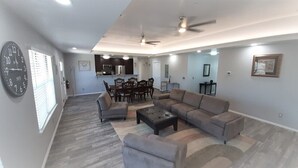 A spacious living room with a sectional sofa, a coffee table, and a dining area with chairs and a table. - Private Bedroom Suite - Communal House near Integris Private (Oklahoma City)