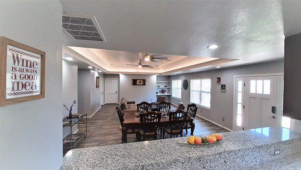 A modern kitchen with granite countertops, a dining area with wooden chairs, and a ceiling fan. - Private Bedroom Suite - Communal House near Integris Private (Oklahoma City)