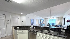 A modern kitchen with white cabinetry, granite countertops, and stainless steel appliances.