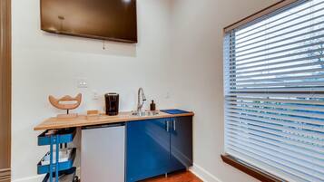 A compact kitchenette with a built-in dishwasher, a coffee maker, and a sink.