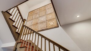A staircase with a wooden handrail and a decorative panel on the wall.