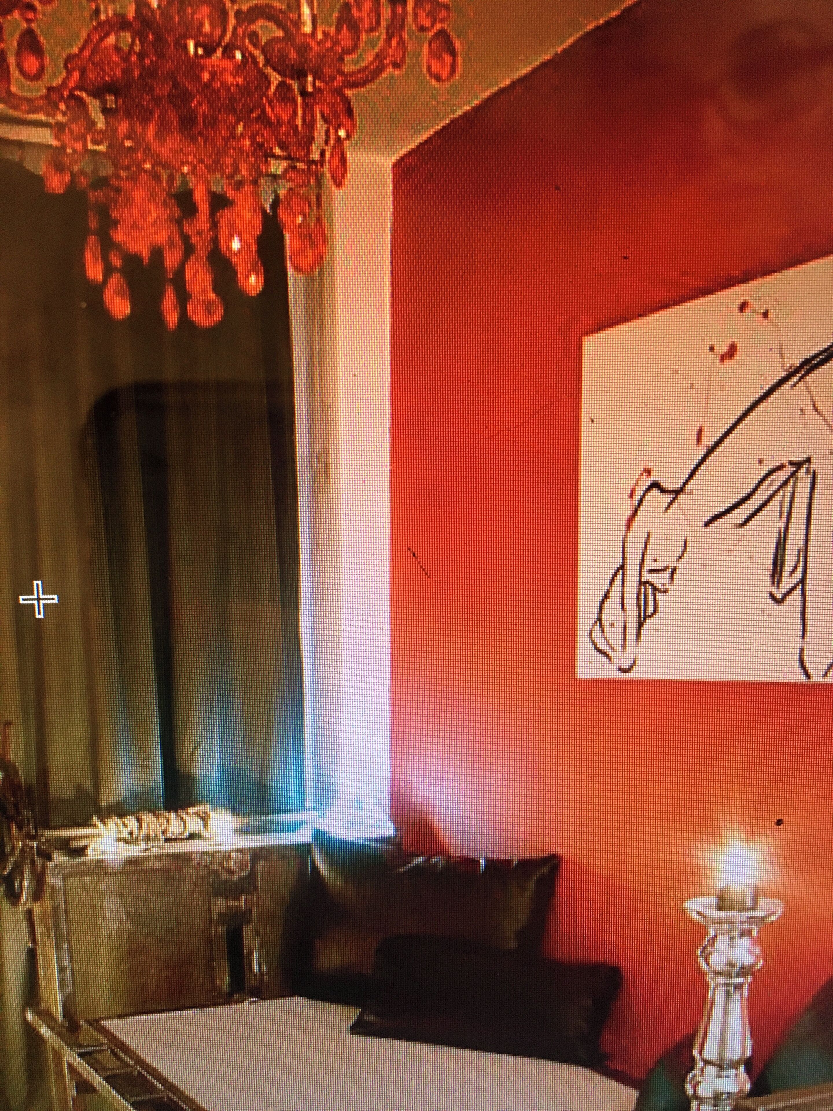 A room with a bed, a chandelier, and a wall with a painting.
