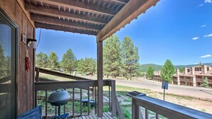 A wooden porch with a grill and outdoor seating. - Angel Fire Condo: Walk to Slopes & Trails! (Angel Fire)