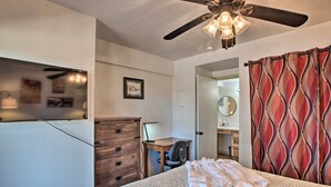 A bedroom with a bed, a desk, a dresser, a ceiling fan, and a bathroom visible through an open door. - Angel Fire Condo: Walk to Slopes & Trails! (Angel Fire)