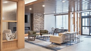 Amplio salón con diseño moderno, que presenta una pared de acento de piedra, techo de madera y un gran ventanal que proporciona luz natural.