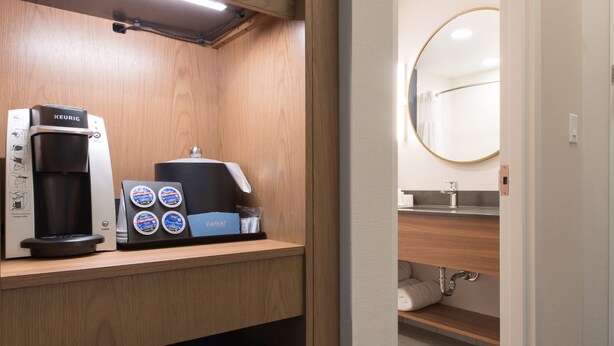 A compact kitchenette with a Keurig coffee maker, a coffee pod dispenser, and a small trash bin. - Fairfield Inn & Suites by Marriott Penticton (Penticton)