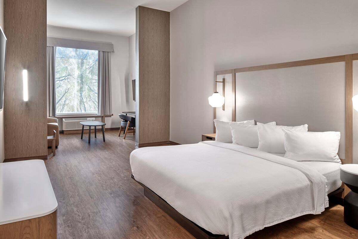 Ein modernes Hotelzimmer mit einem großen Bett, einem Schreibtisch und einem Sessel.