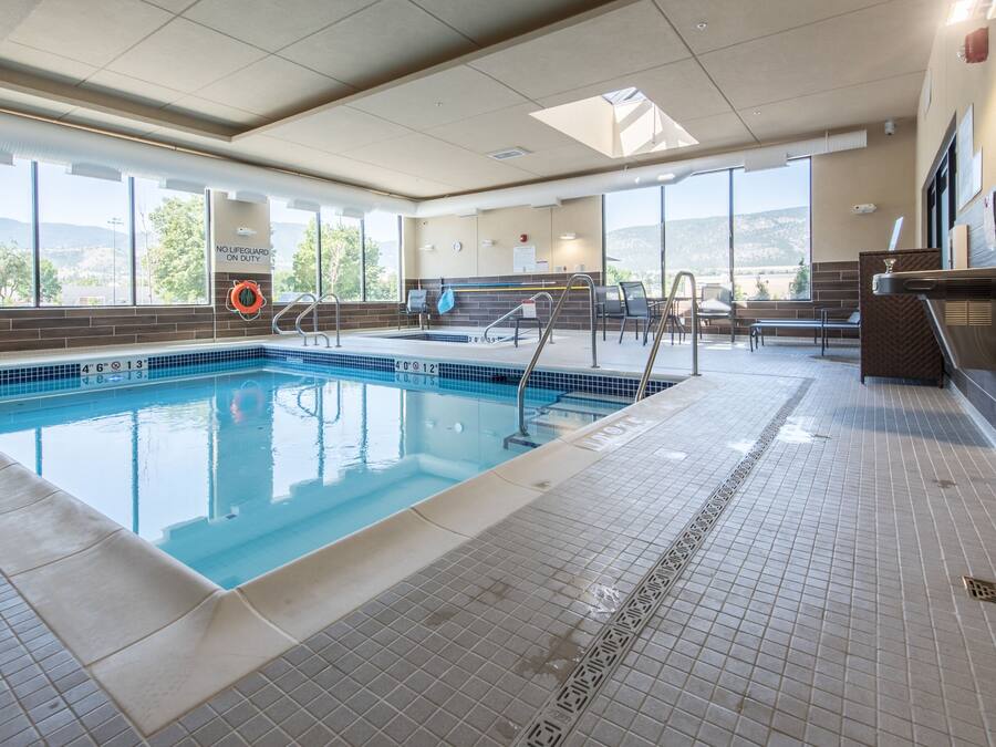 A swimming pool with clear water, tiled floor, and a lifeguard chair.