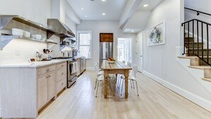 Una cocina moderna con una isla central, electrodomésticos de acero inoxidable y un comedor con mesa y sillas de madera.