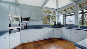 A modern kitchen with white cabinetry, a built-in oven, a microwave, and a large window offering a view of trees. - SOMETHING FOR EVERYONE (Somers)