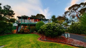 A two-story house with a balcony, surrounded by lush greenery and a well-maintained lawn. - SOMETHING FOR EVERYONE (Somers)