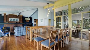 A spacious dining area with a wooden table and chairs, a brick fireplace, and a large window offering a view of the outdoors. - SOMETHING FOR EVERYONE (Somers)