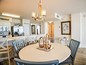 A modern kitchen with white cabinets, a stainless steel refrigerator, and a chandelier.