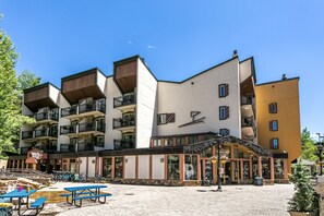 Un immeuble à plusieurs étages doté de balcons, d’un café au rez-de-chaussée et d’une terrasse.