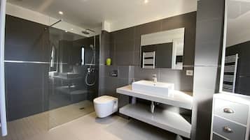 A modern bathroom with a glass shower enclosure, a white sink, and a large mirror.