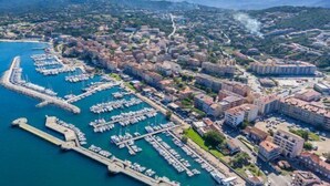 An aerial view of a coastal town with a marina filled with boats, surrounded by residential buildings and mountains in the background. - MARINA D'ORU - Comfortable studio in town center (M) (PROPRIANO)