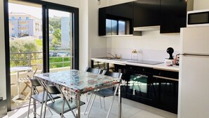 A modern kitchen with black cabinets, a white refrigerator, and a dining table with chairs. - MARINA D'ORU - Comfortable studio in town center (M) (PROPRIANO)