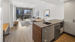 A modern kitchen with a central island, a dining area with a view, and a living space with a sofa and a coffee table. - Lucid Living Brisbane (South Brisbane)
