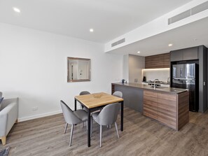 A modern kitchen with a wooden island, built-in appliances, and a dining area with a table and chairs. - Lucid Living Brisbane (South Brisbane)