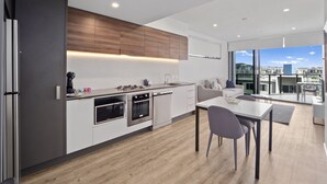 A modern kitchen with a dining area, large windows, and a view of the city. - Lucid Living Brisbane (South Brisbane)
