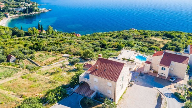 A coastal property with a swimming pool, stone buildings, and a view of the sea.