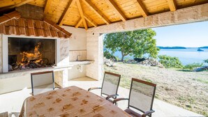 A wooden-beamed ceiling, a fireplace, a table with chairs, and a view of a lake.