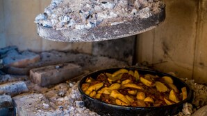 A cooking area with a pan of potatoes being roasted over an open fire.
