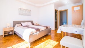 A bedroom with a bed, bedside table, and a small table with a chair.