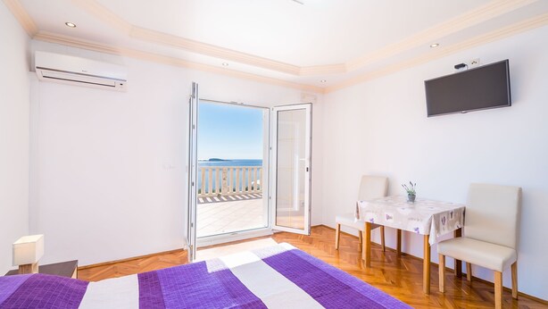 Ein Zimmer mit einem Bett, einem Tisch, Stühlen, einem Fernseher und einem Balkon mit Blick.