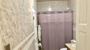 Een badkamer met marmeren wanden, een toilet, een wastafel en een douchegordijn.