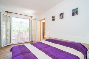 Ein Schlafzimmer mit einem Bett, einer Schiebetür zum Balkon und zwei an der Wand befestigten Bildern.