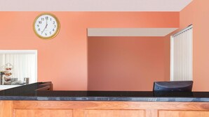 Une cuisine avec un plan de travail en bois, une horloge au mur et une fenêtre avec des stores.