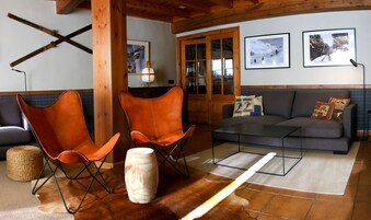 Una sala de estar acogedora con un sofá, dos sillones de cuero, una mesa de centro y piso de madera.