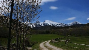 A dirt path leading to a mountain range with snow-capped peaks. - Lo Paller (Alt Aneu)
