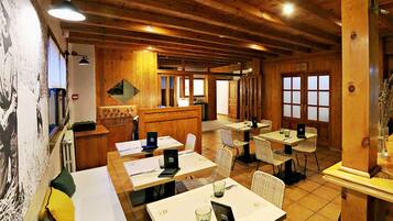 Un interior de madera con varias mesas y sillas, una recepción y un ventanal grande.