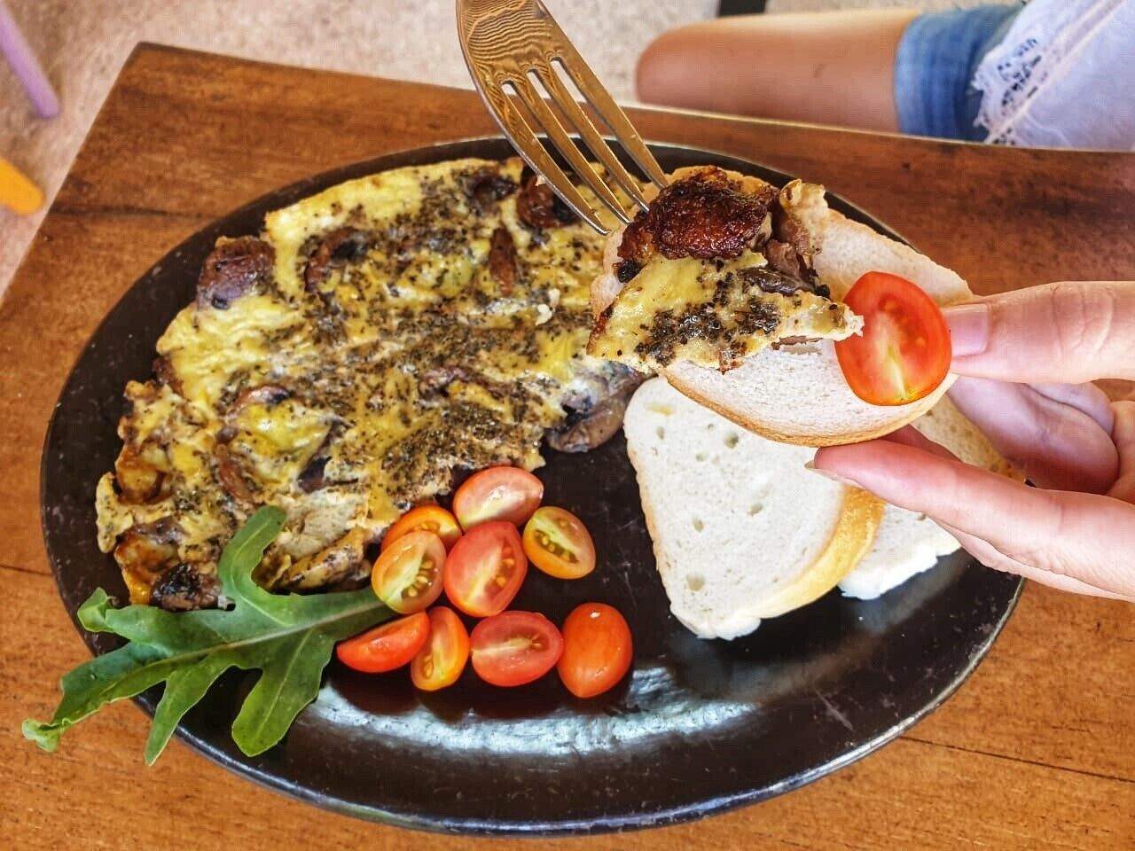 A plate with a breakfast dish, including toast and cherry tomatoes, on a table.