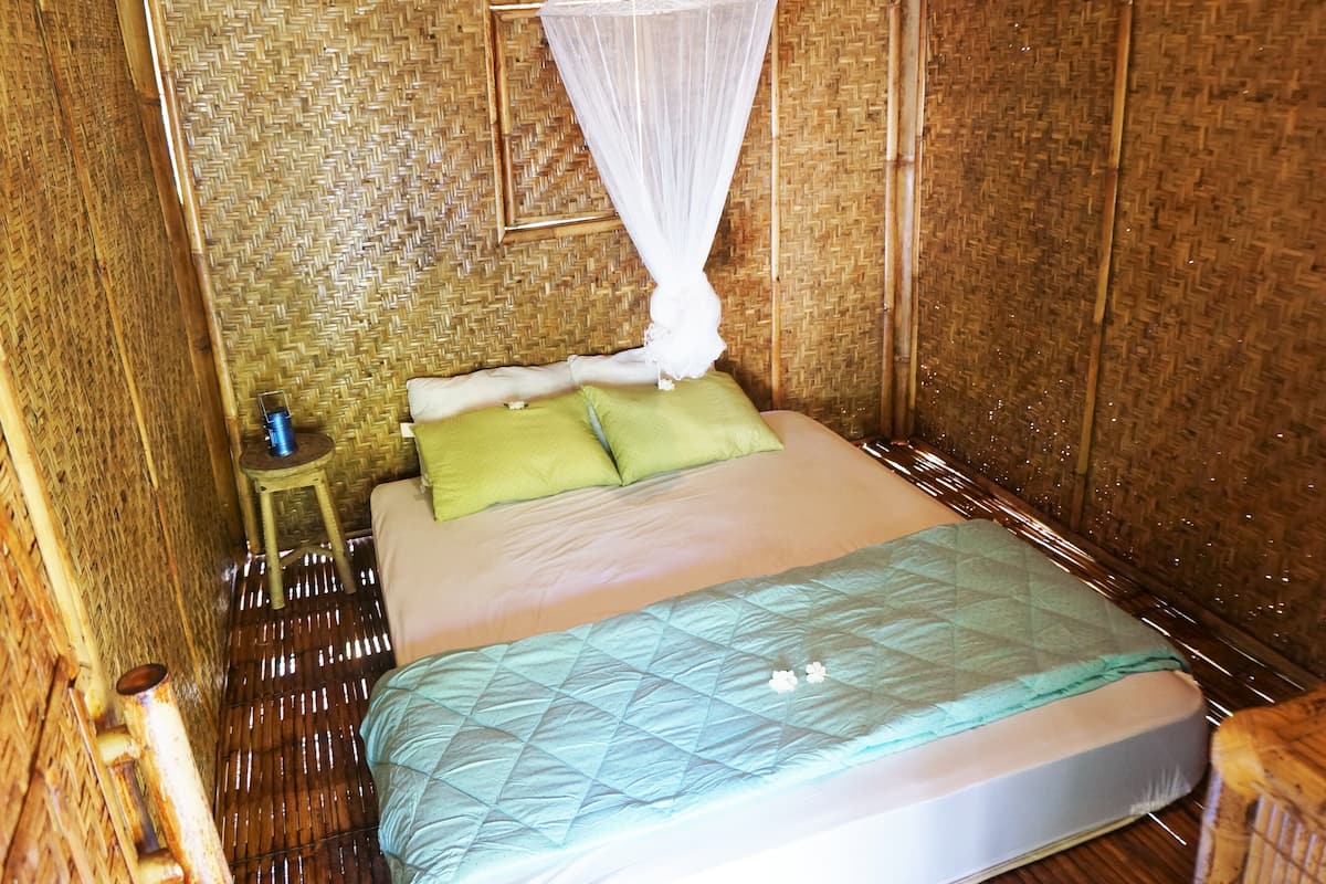 Una habitación con una cama, un taburete pequeño y una mosquitera.