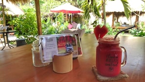Un tavolo con un barattolo di vetro contenente una bevanda rosa, un menu e una tazza di legno.
