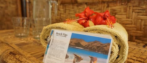 A wooden table with a rolled-up towel and a beach tips sign.