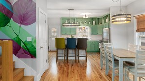 A modern kitchen with green cabinets, a wooden dining table, and three chairs.
