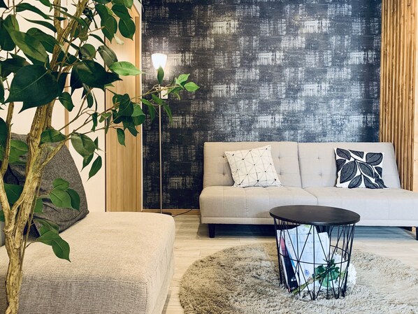 A modern living room with a sofa, a round coffee table, and a large plant.