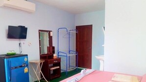 A room with a bed, a small desk, a mirror, a wardrobe, a blue chair, a television, and a door. - Ban Chomlay Resort Satun (La-ngu)