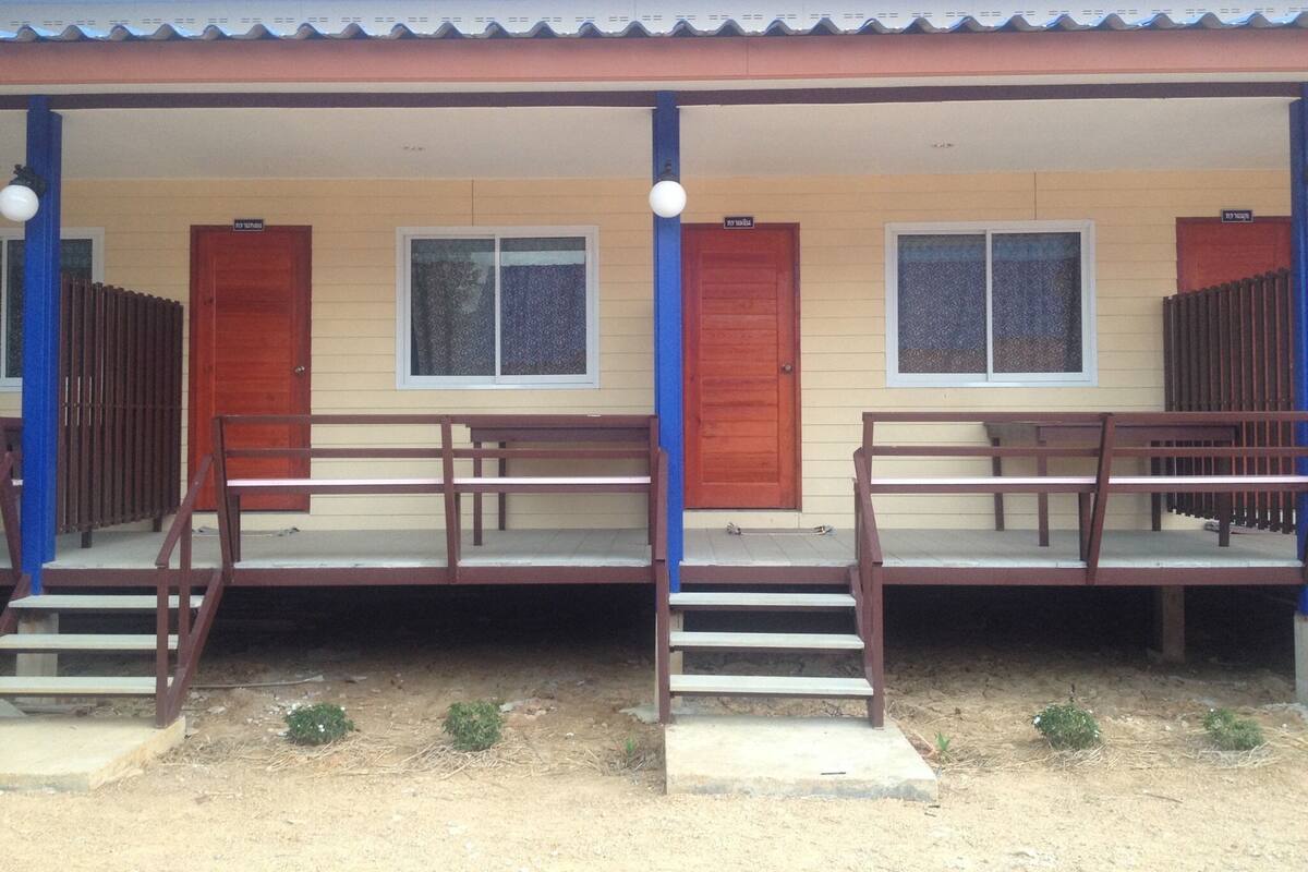 A building with two wooden doors, a covered porch, and a small garden area.
