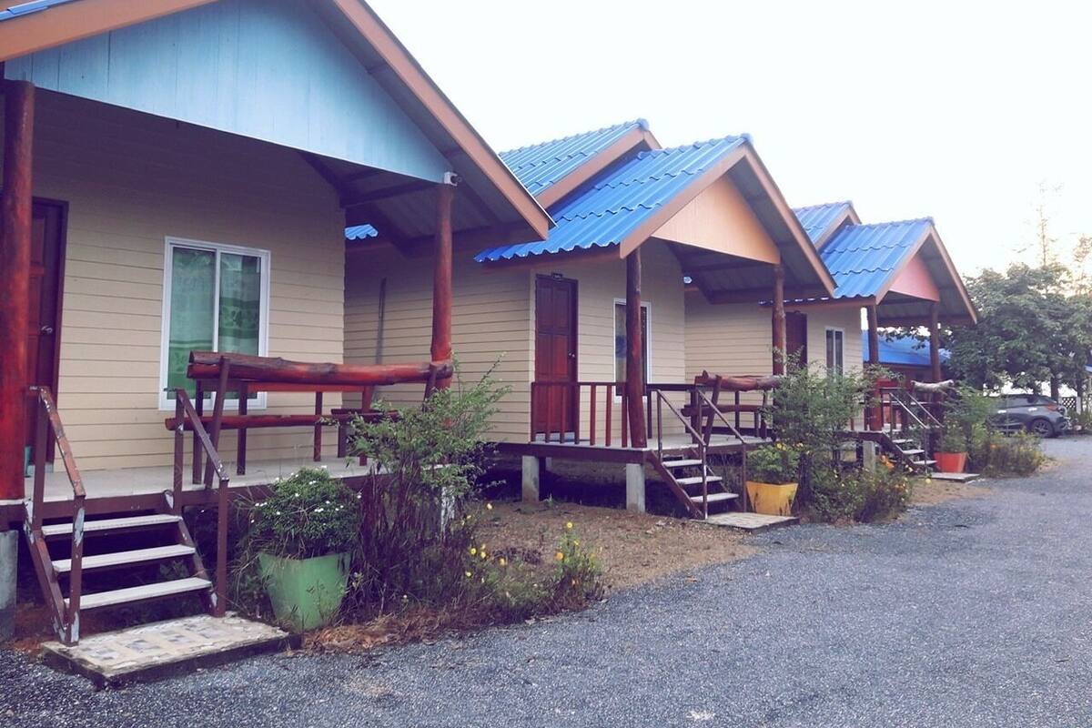 A row of cabins with wooden steps leading to the entrance, a covered porch, and a gravel driveway.